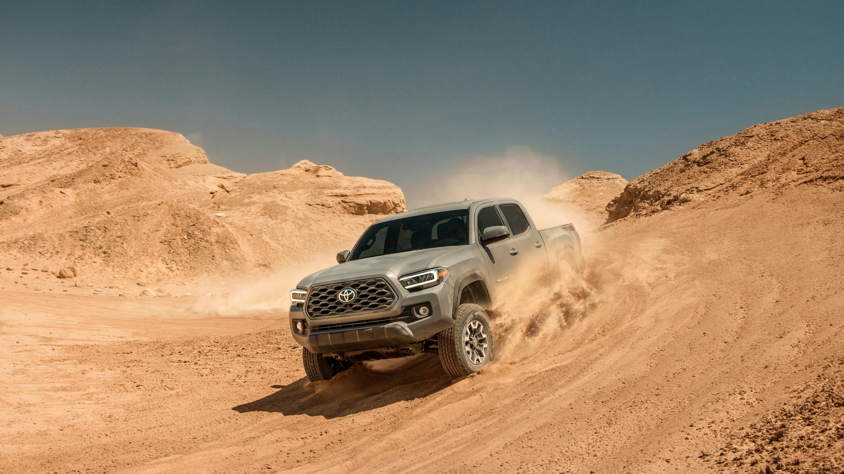 gray toyota tacoma on steep decline on dirt path