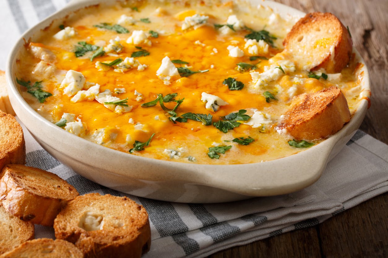 Homemade hot buffalo chicken dip with crostini close up in baking dish.