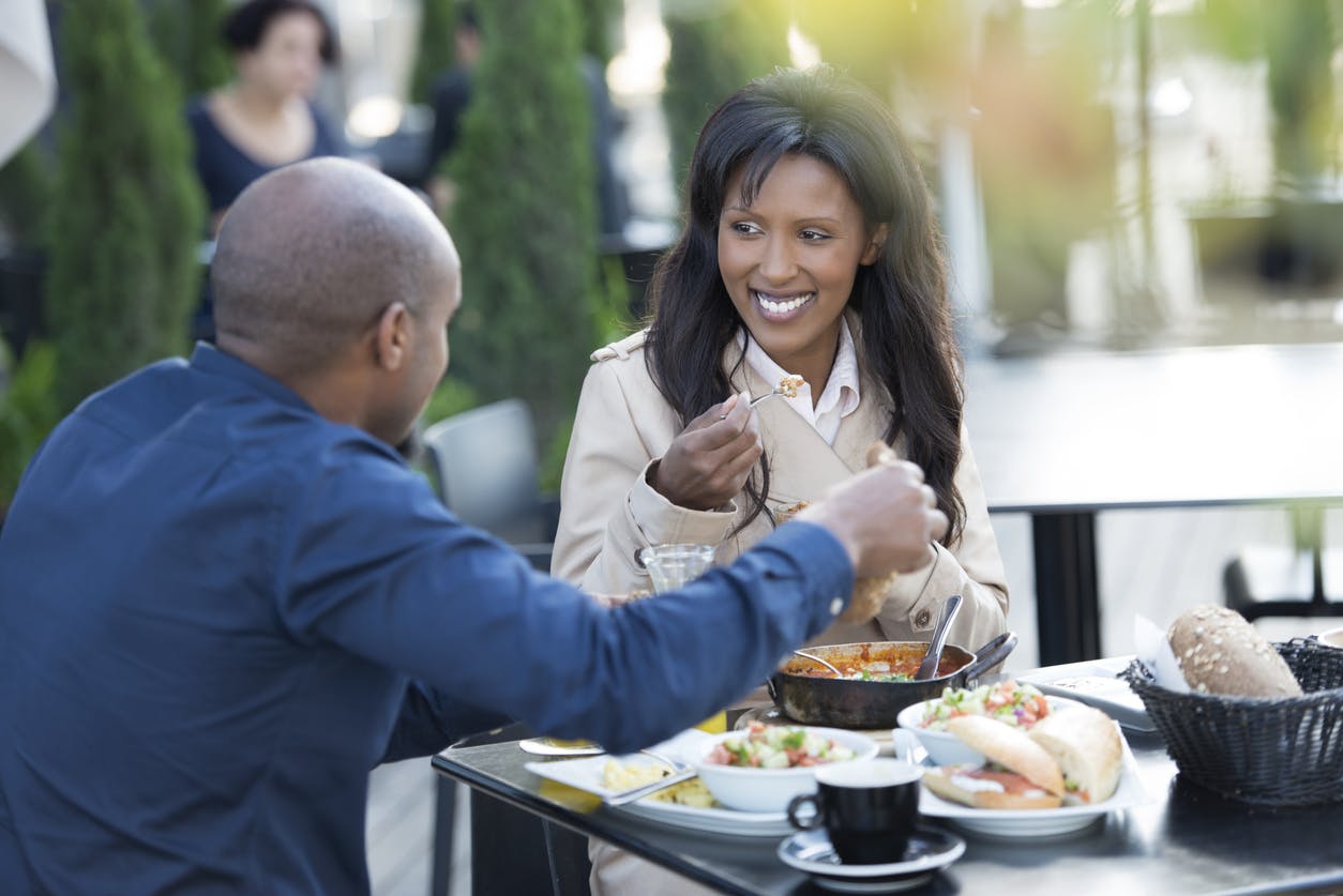 Couple eating breakfast at restaurant with outdoor seating.