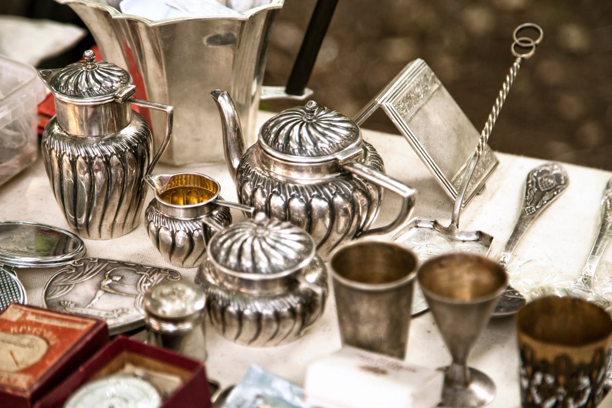 Antique silver teapots, creamer and other utensils at a flea market