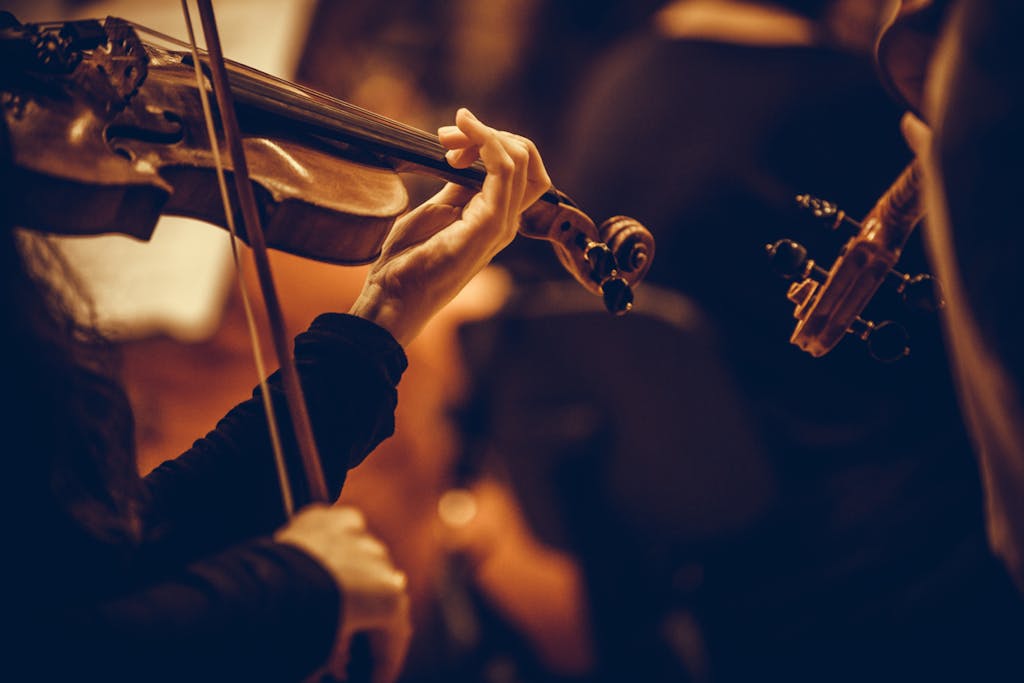 Close up shot of a woman performing on a violin during a concert.