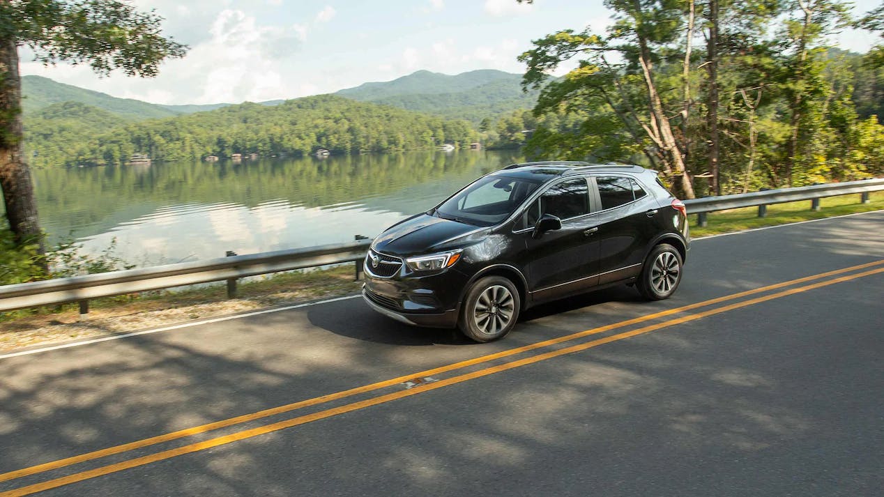 buick-encore-cg-gallery-lg Black Buik Encore driving roadside a scenic pond and trees