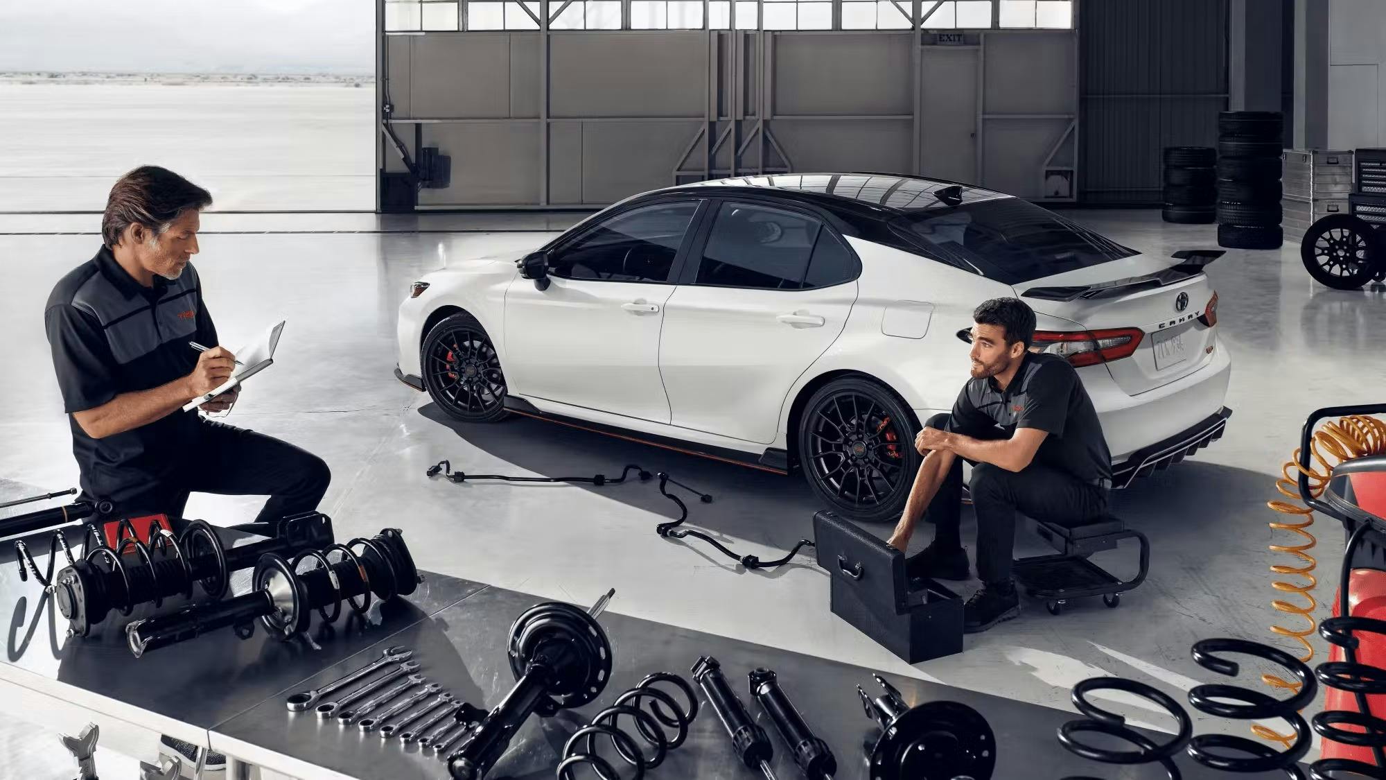 two toyota technicians servicing a white camry in the shop