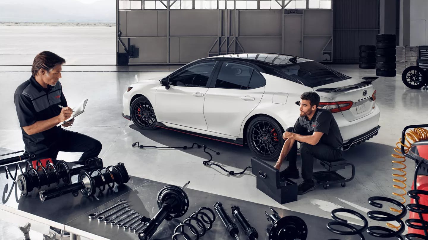 two men servicing white toyota camry