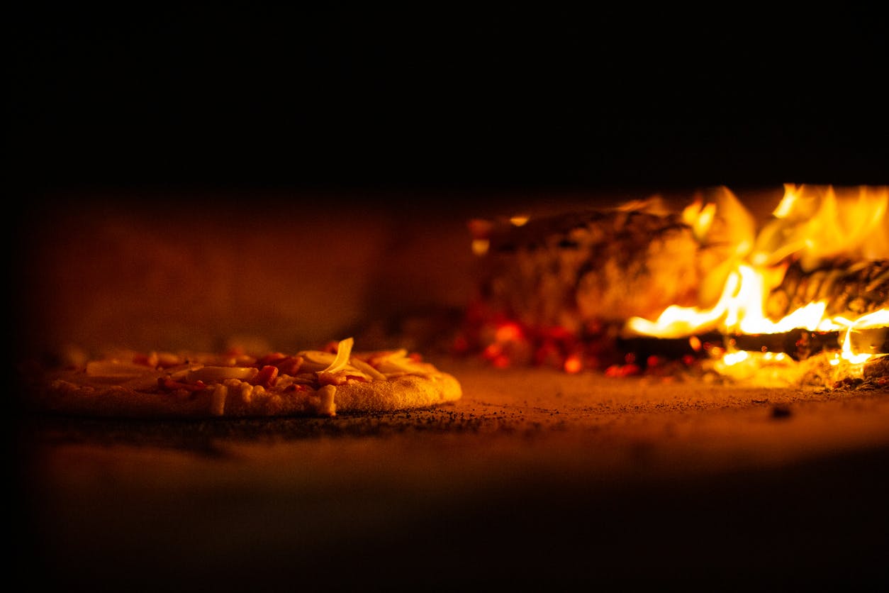 Pizza being cooked in an authentic wood fired oven