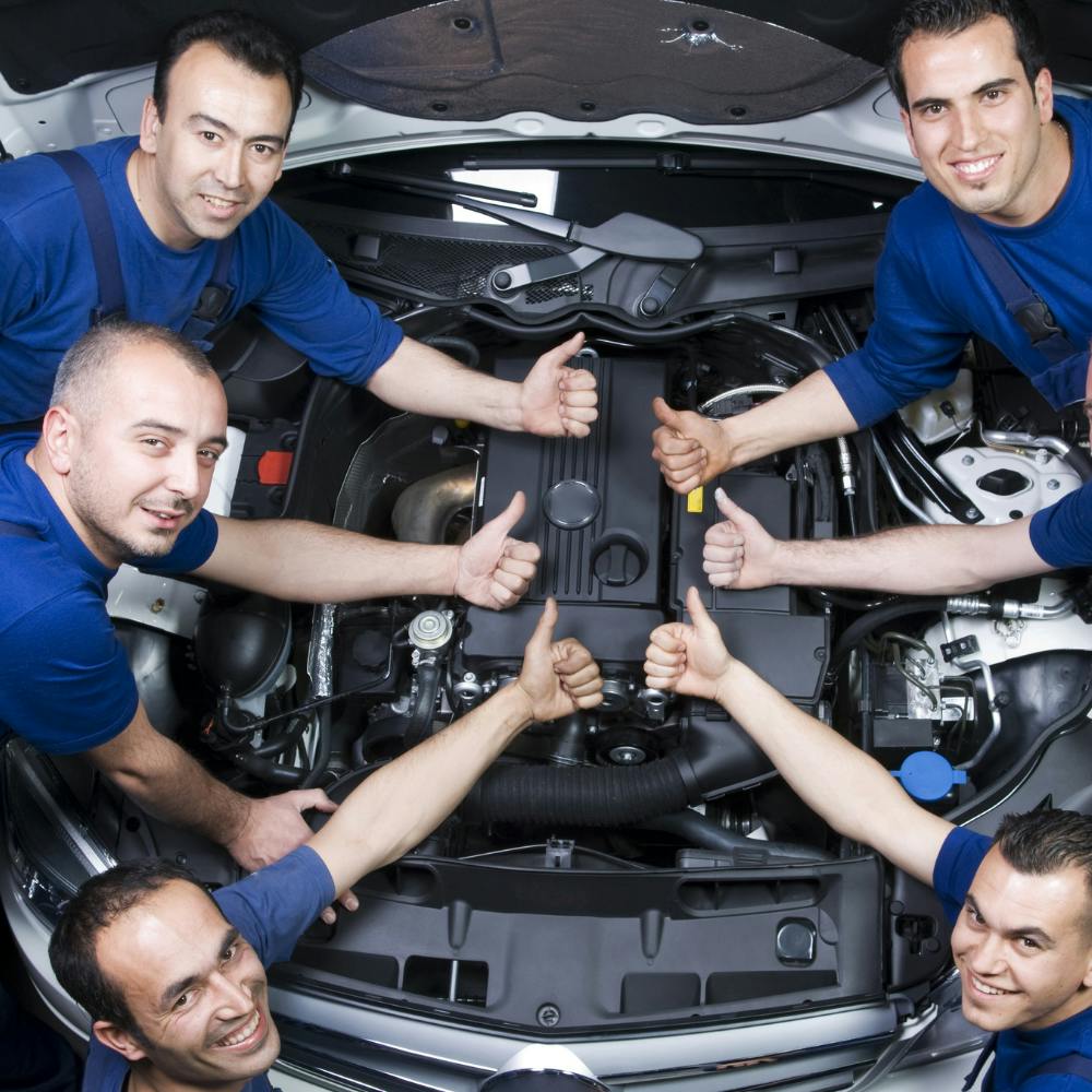 Team of technicians by engine of vehicle