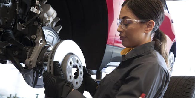 female chevy technician fixing brake