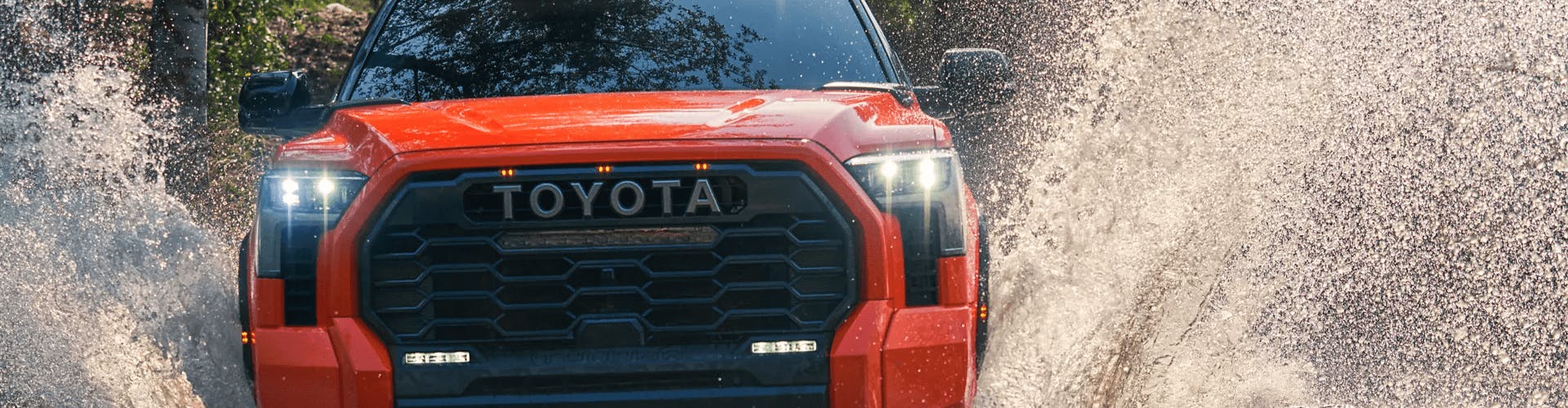 Red Toyota Tundra driving through a stream