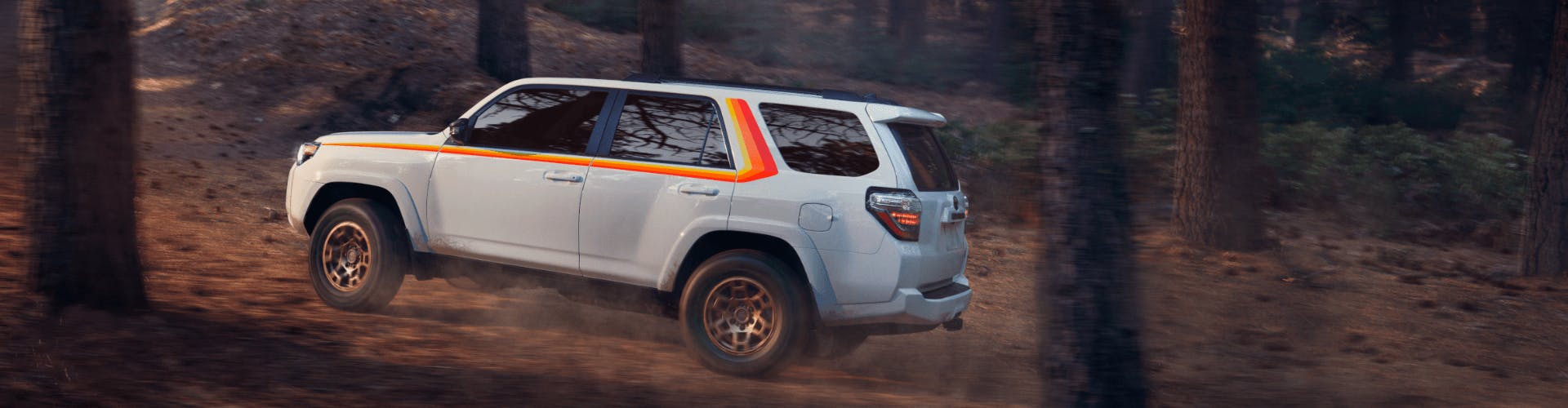 White Toyota 4Runner driving off-road surrounded by trees