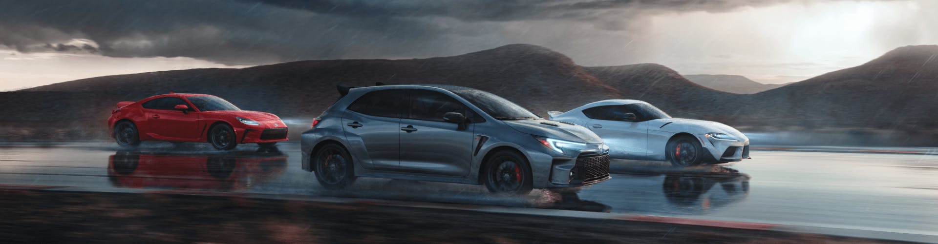 Silver, Red and White Toyota GR's driving on open road under dark clouds