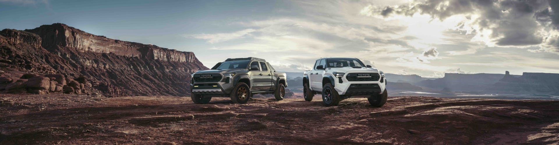 Black and Red Toyota Tacoma trucks parked in front of mountains