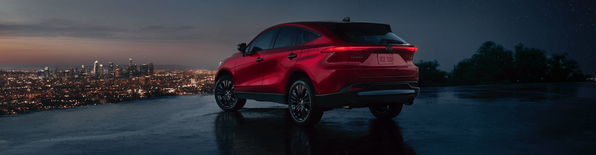 MY23 Toyota Venza 1920×500-min Red Toyota Venza parked on blacktop overlooking the city