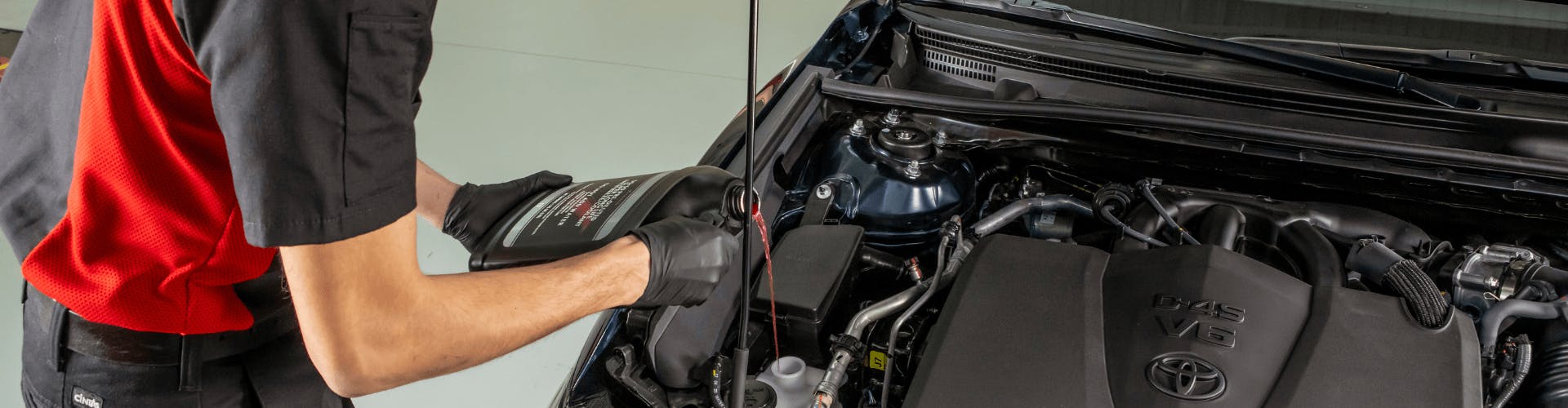 Toyota service technician putting oil in vehicle