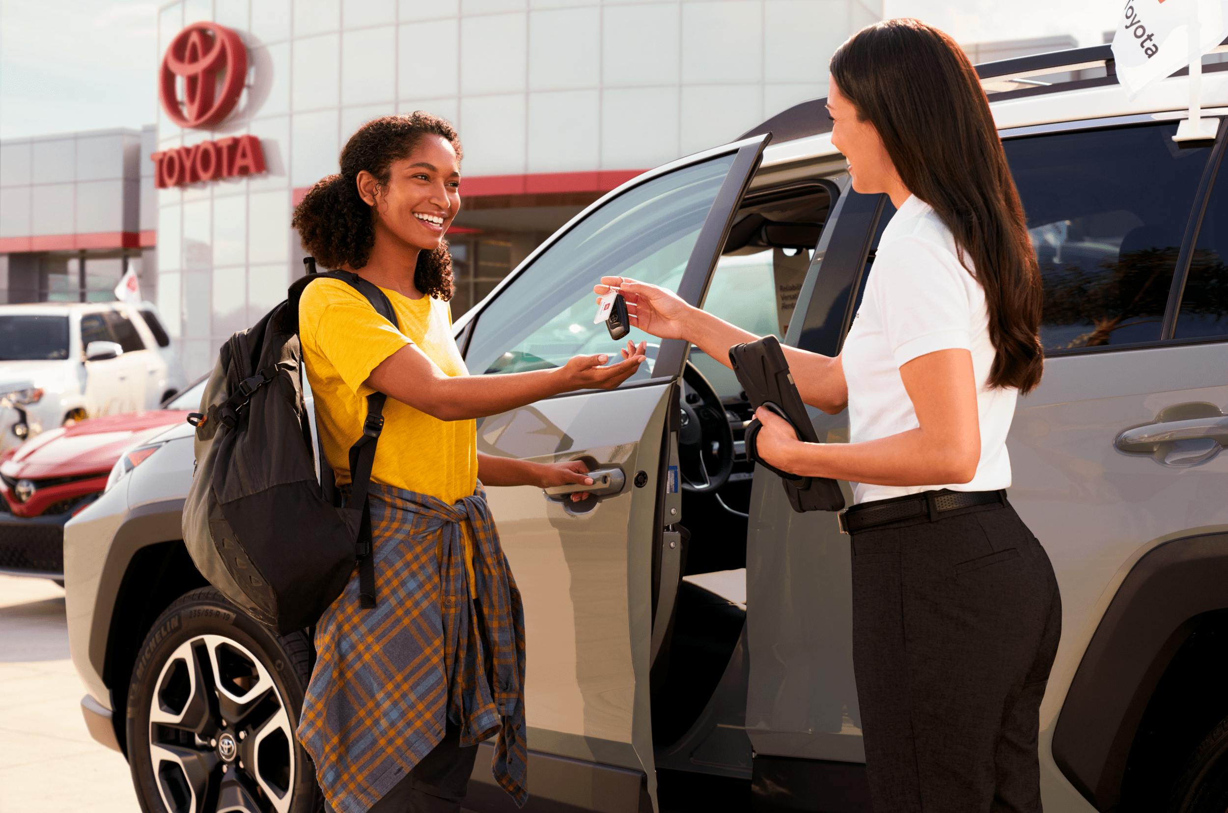 women handing over keys for rental vehicle at dealership