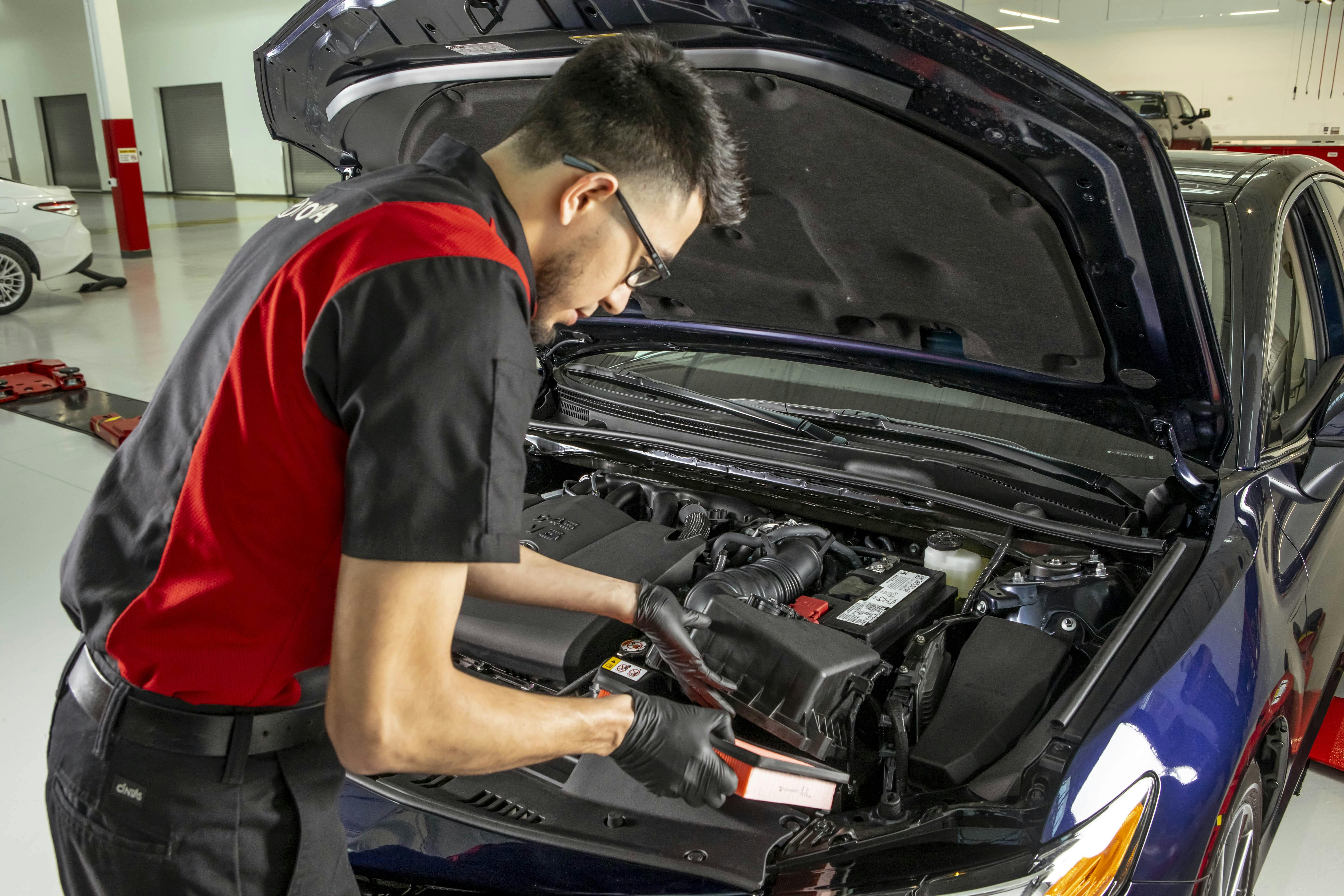 technician working under hood of vehicle