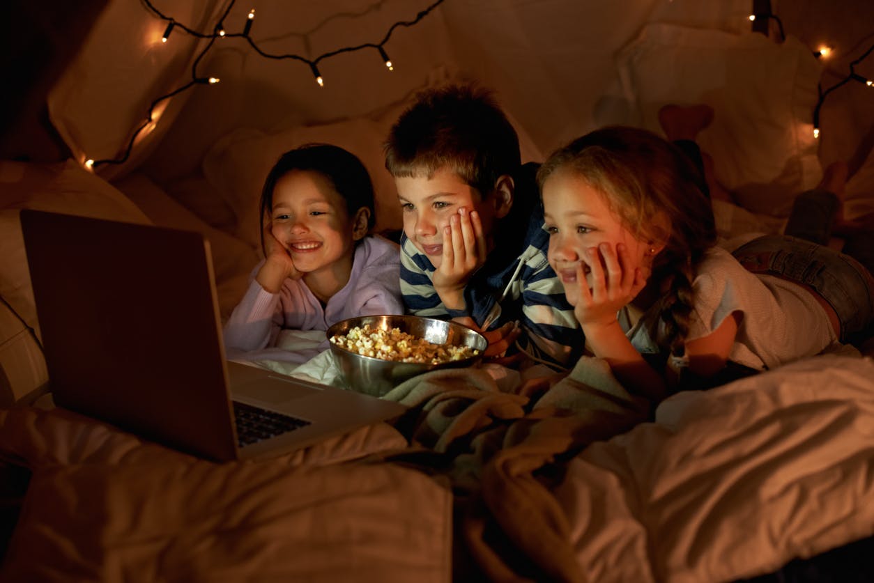 children watching a movie in a blanket fort