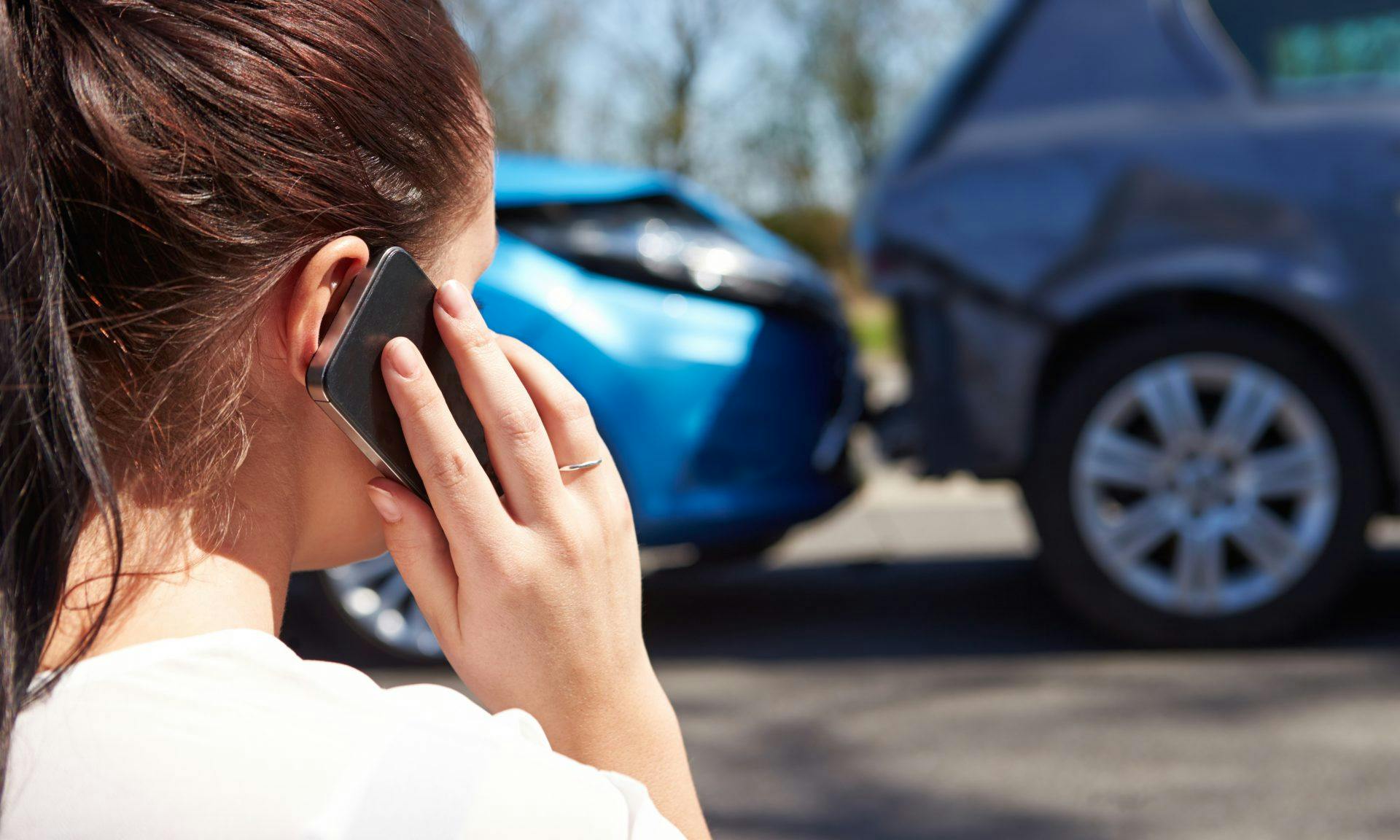 women on phone in front of car accident