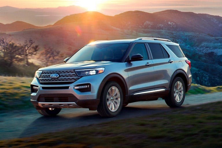 Ford Explorer driving on open road with mountains in the back