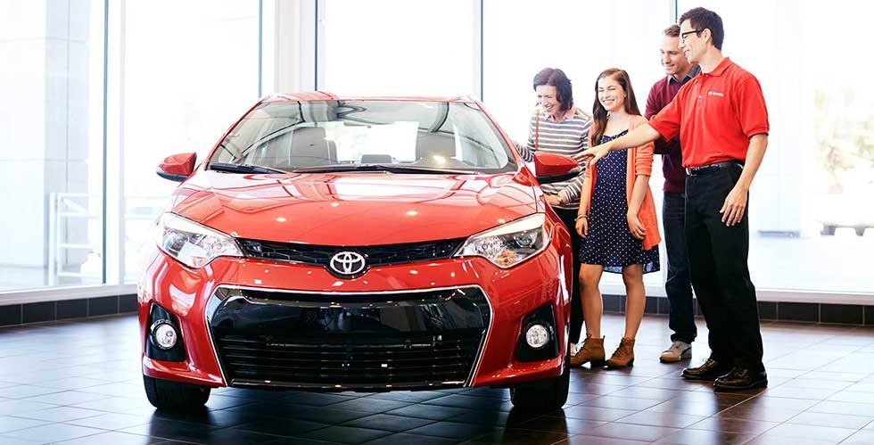 dealership staff looking at red car