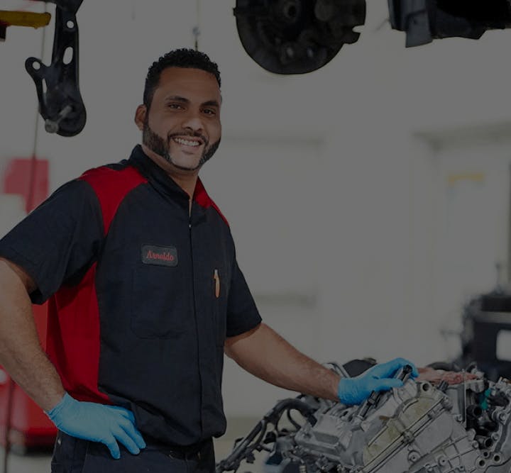 smiling technician standing beside vehicle with open hood