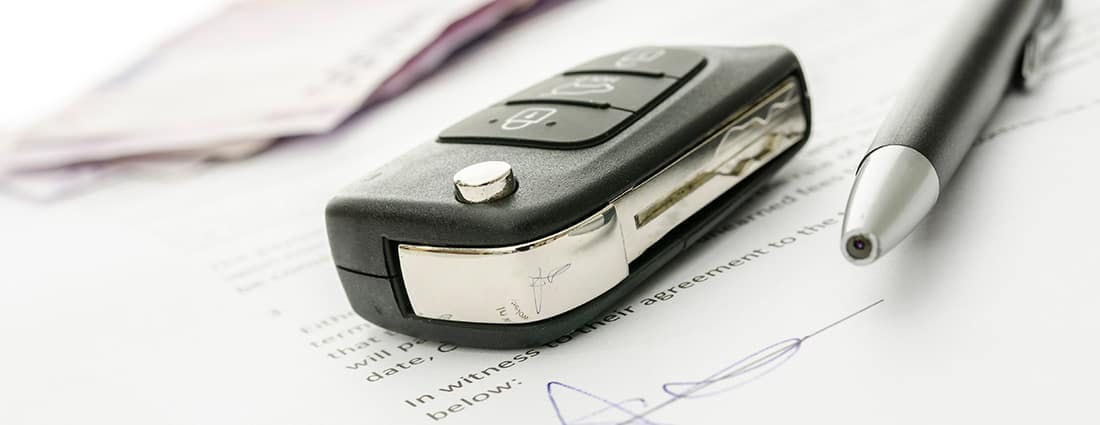 keys beside pen on desk with papers