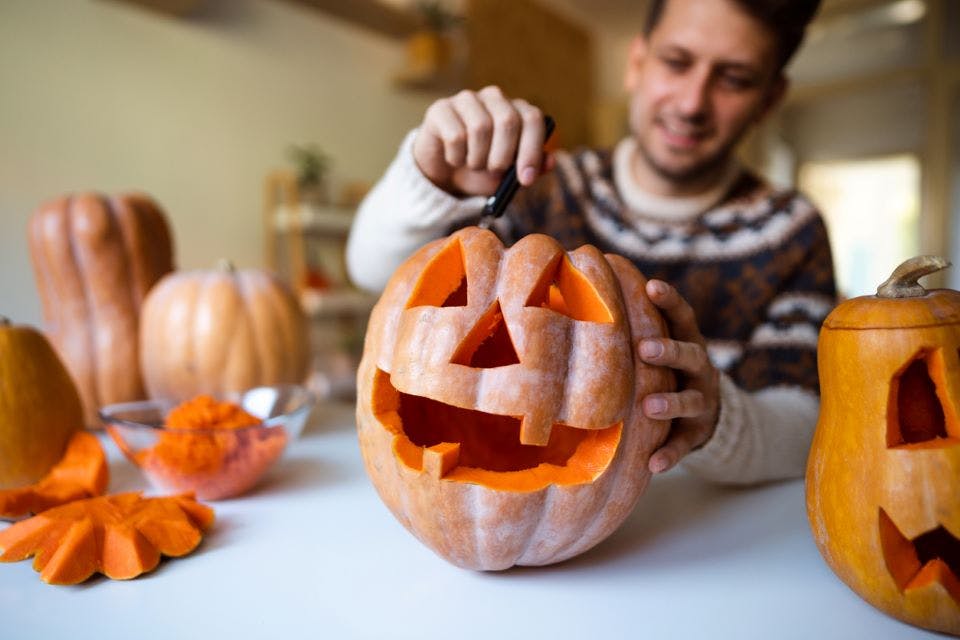 Happy man carving a pumpkin for Halloween