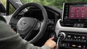 man sitting in vehicle pressing the start engine button