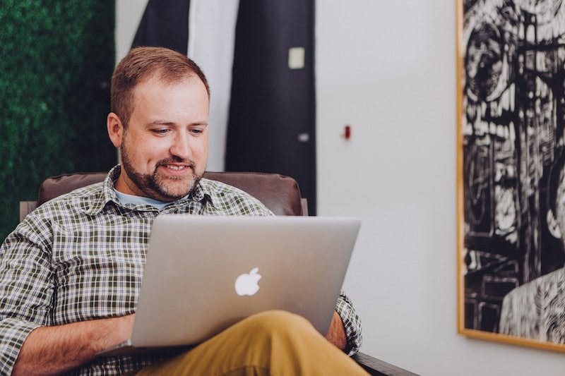 man at home sitting on couch  looking at laptop
