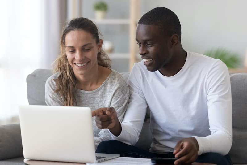 woman and man sitting on couch in front of laptop