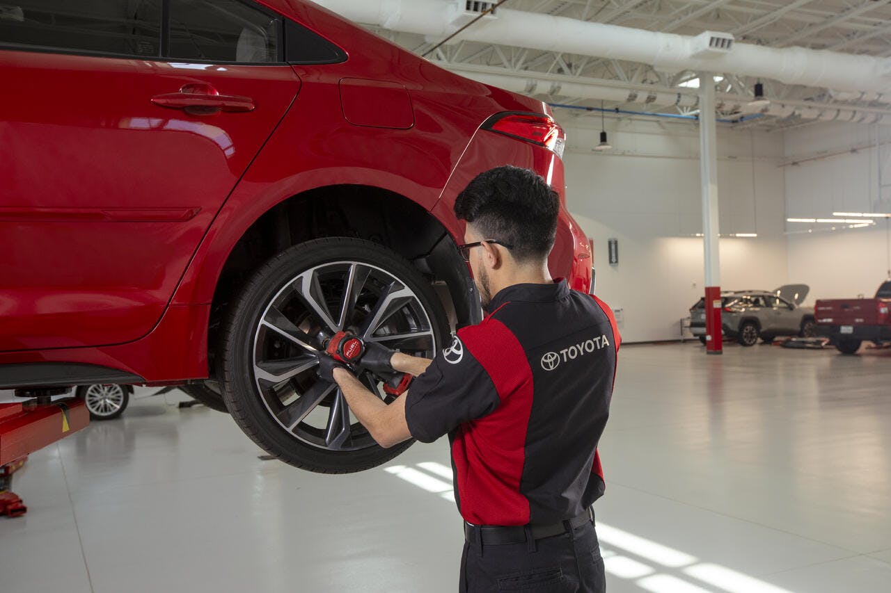 tech working on tire of red vehicle