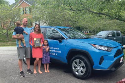 family in front of blue toyota