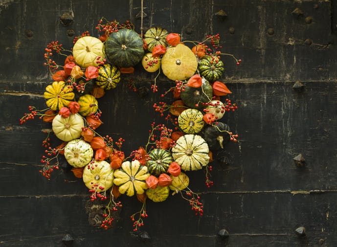 Handmade wreath of small pumpkins and zucchini on a vintage door Halloween pumpkins