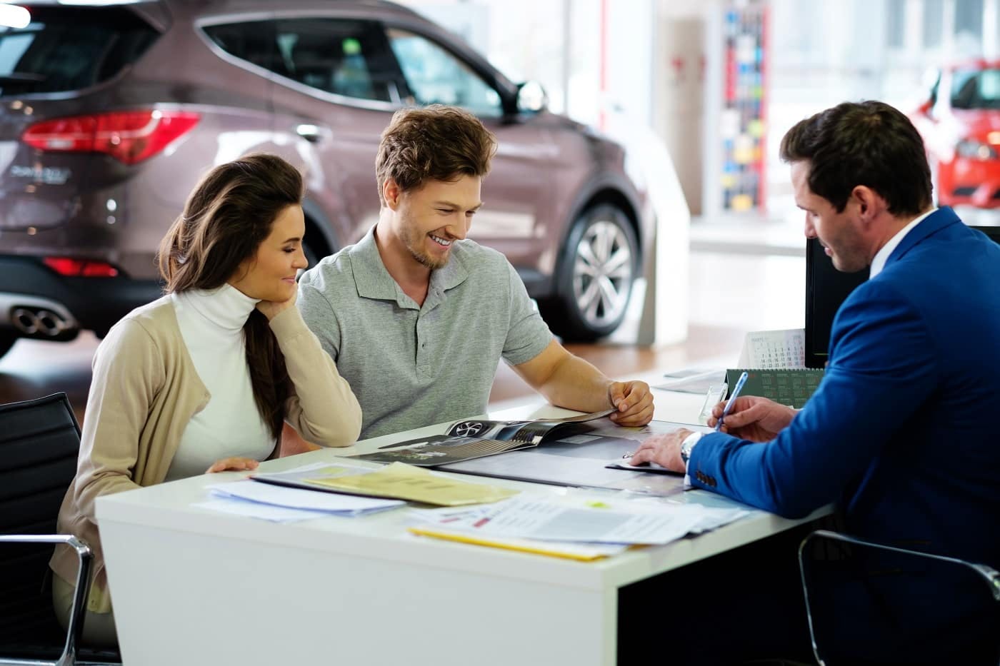 couple sitting at desk with salesperson inside showroom
