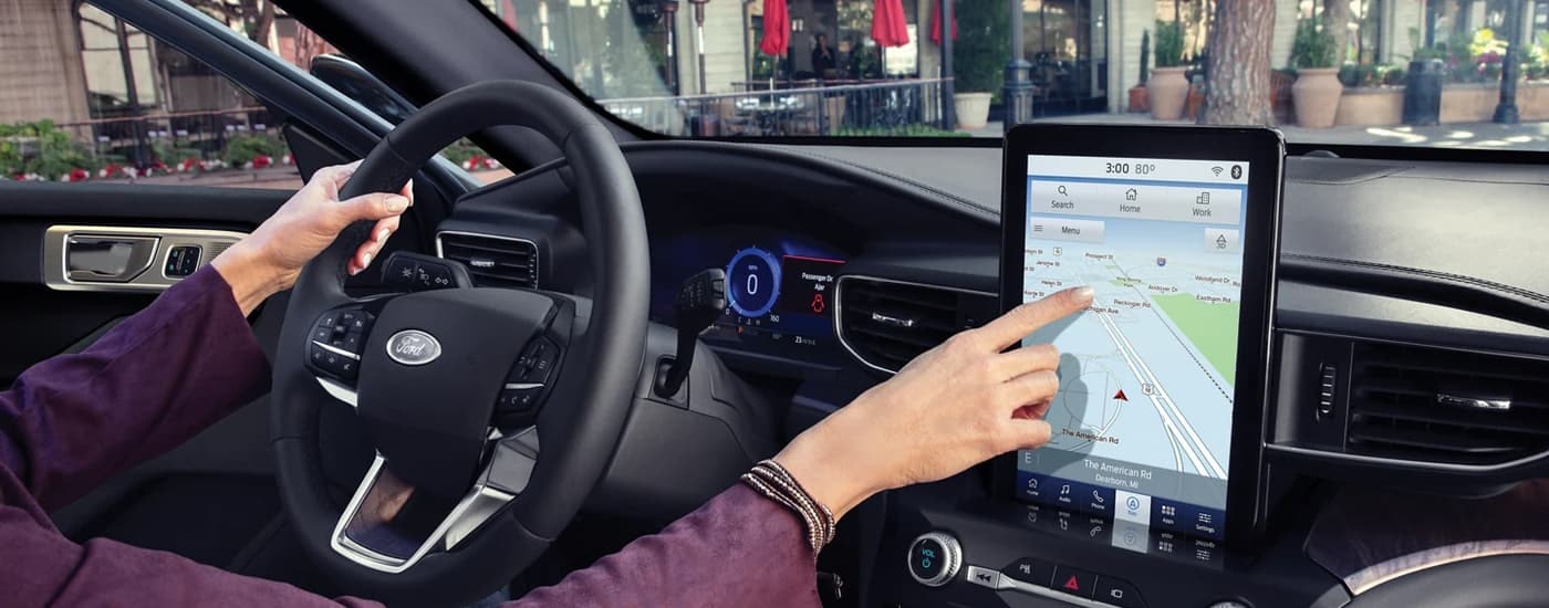 A person is shown using the infotainment screen in a 2023 Ford Explorer.