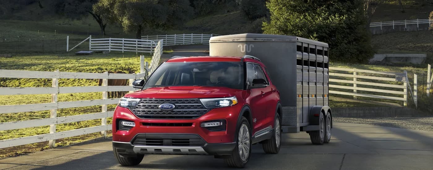 A red 2023 Ford Explorer is shown towing a trailer on a farm.