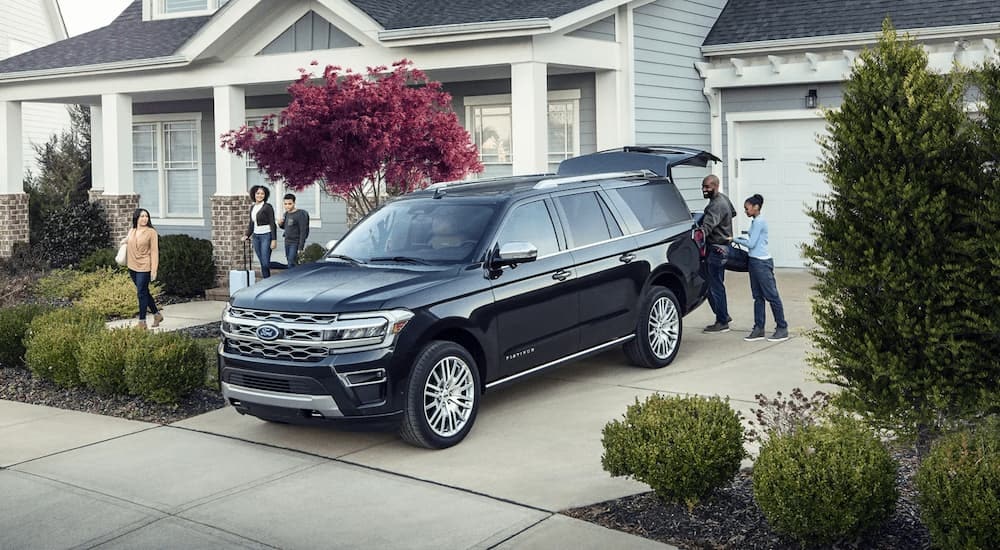 A family is shown putting cargo into the rear of a black 2023 Ford Expedition Platinum parked in a driveway.