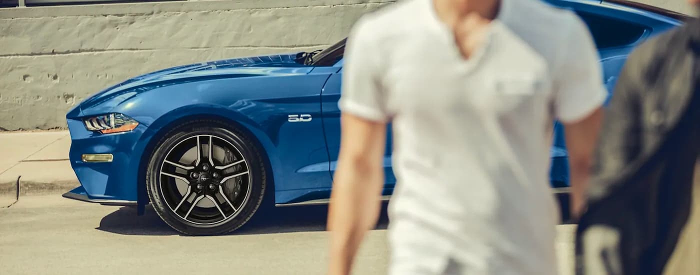 People are shown walking near a blue 2023 Ford Mustang GT.