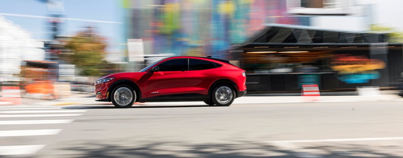 A red 2021 Ford Mustang Mach-E is shown speeding on a city street.