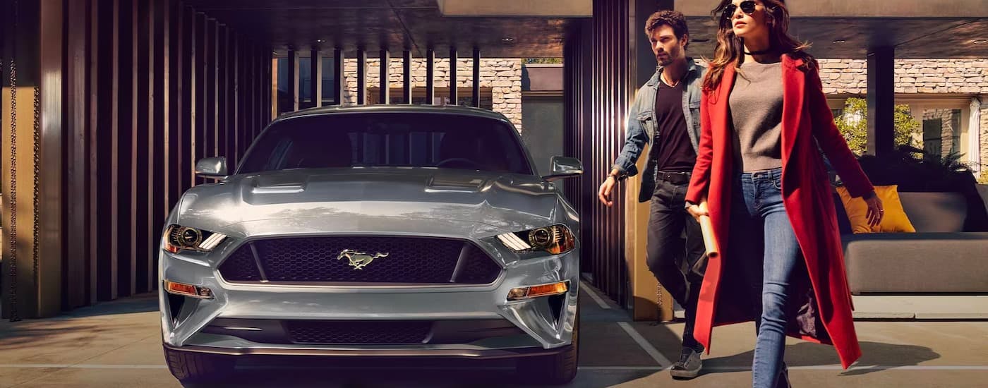 People are shown walking past a grey 2021 Ford Mustang.