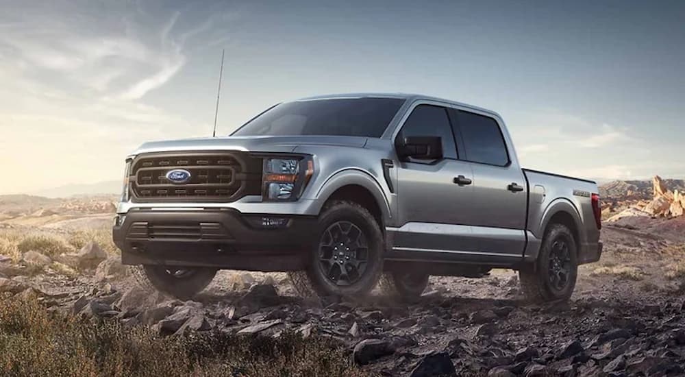 A silver 2023 Ford F-150 Tremor is shown parked in an open dirt lot.