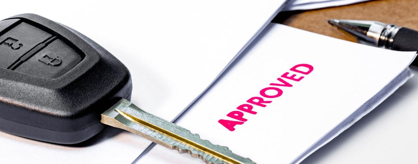 An approved subprime auto loan is shown next to a car key.