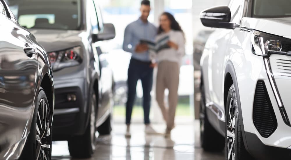 A couple is shown looking at paperwork inside of a car dealership.