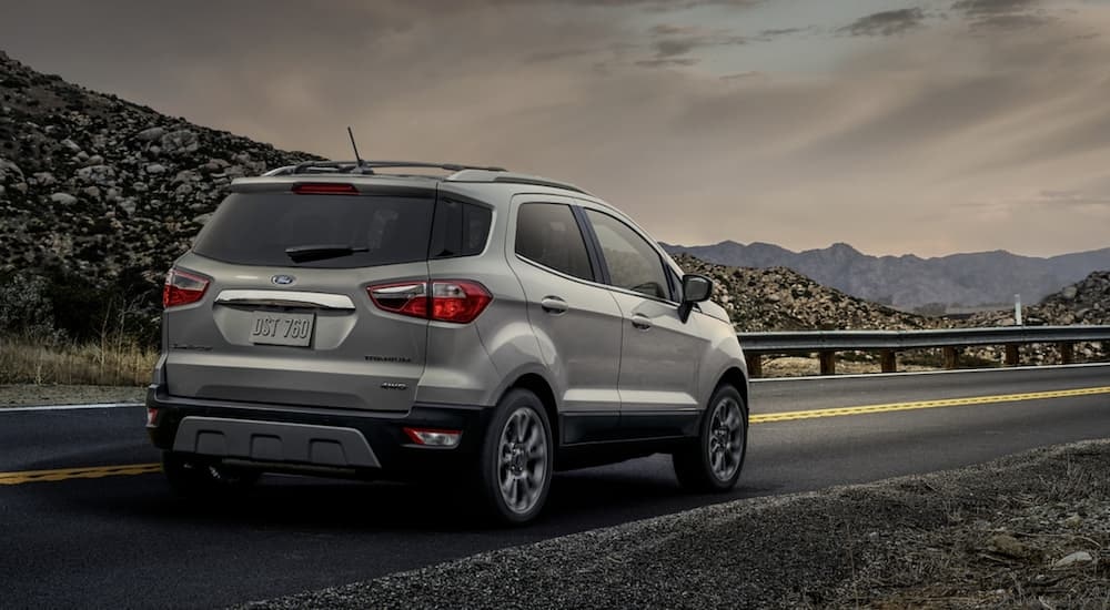 A silver 2020 Ford EcoSport is shown from a rear angle on a mountain highway.