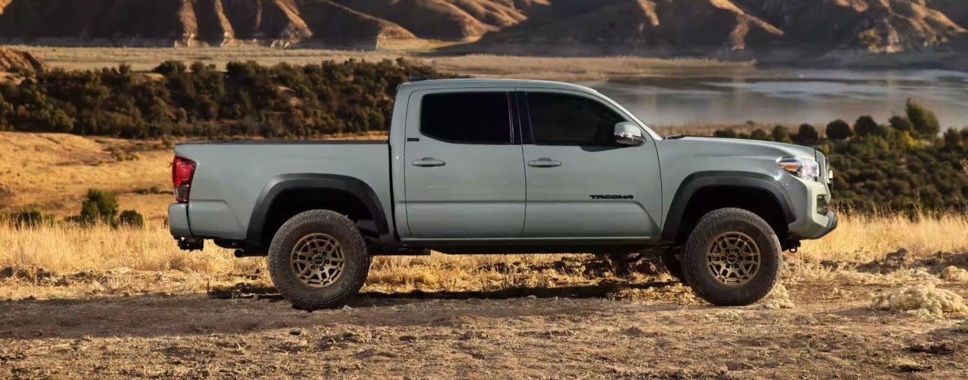 A grey 2023 Toyota Tacoma SR5 Trail Edition is shown from the side in front of a lake.