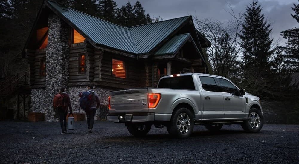 A silver 2023 Ford F-150 Platinum is shown parked near a cabin at night.