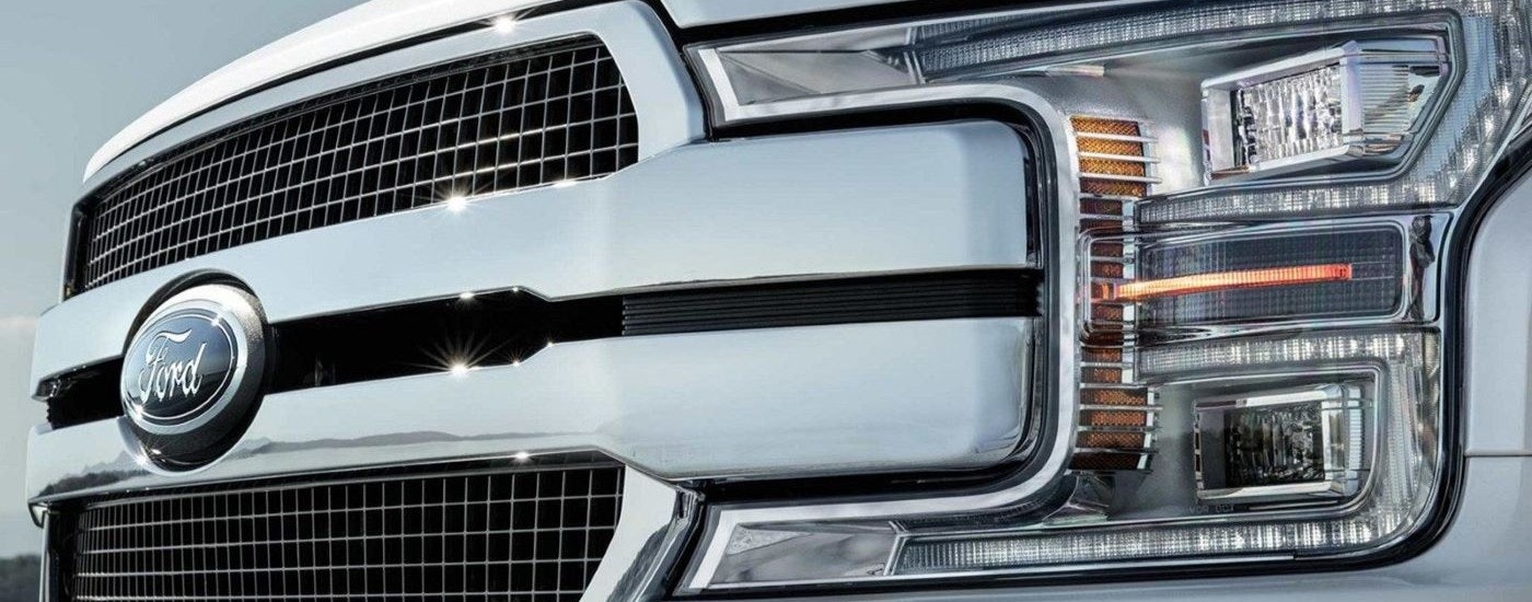 A close up shows the grille and drive side headlight on a white 2020 Ford F-150.