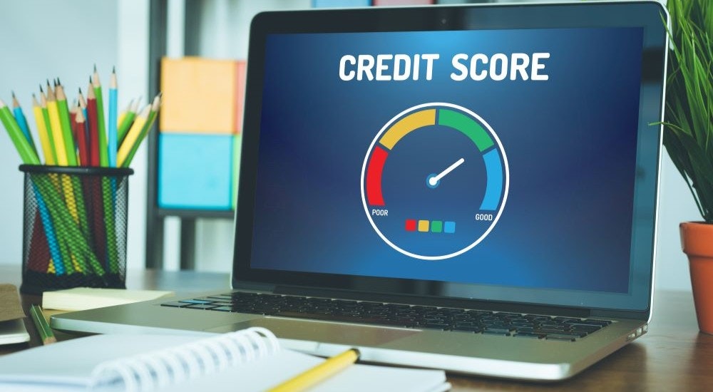 A close up shows a credit score on a laptop screen.