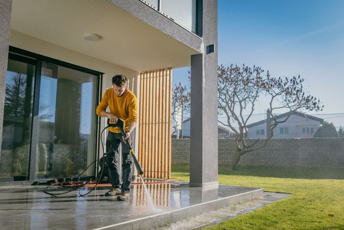 Man pressure washing a patio