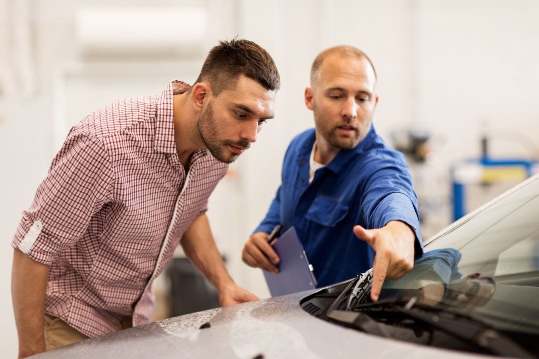 service advisor pointing at the wind shield wiper, customer looking at the car