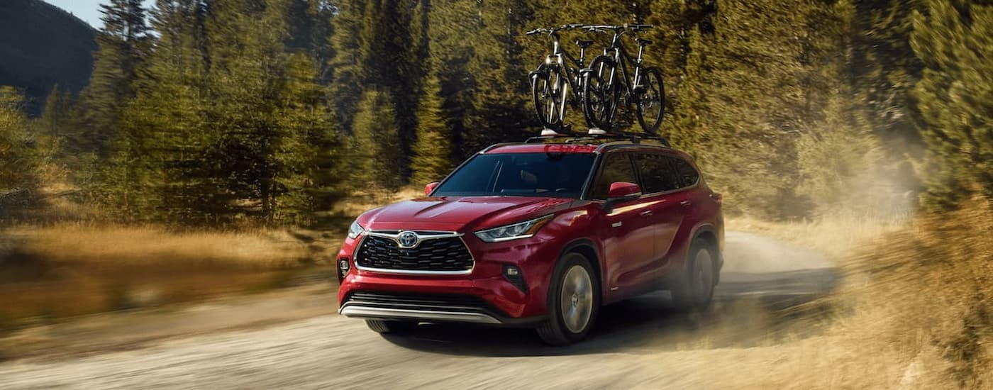 A red 2020 Toyota Highlander is shown driving on a dusty dirt trail.